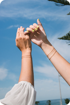 Two girls hold pinky fingers wearing 4 permanent bracelets from the lovers Perth